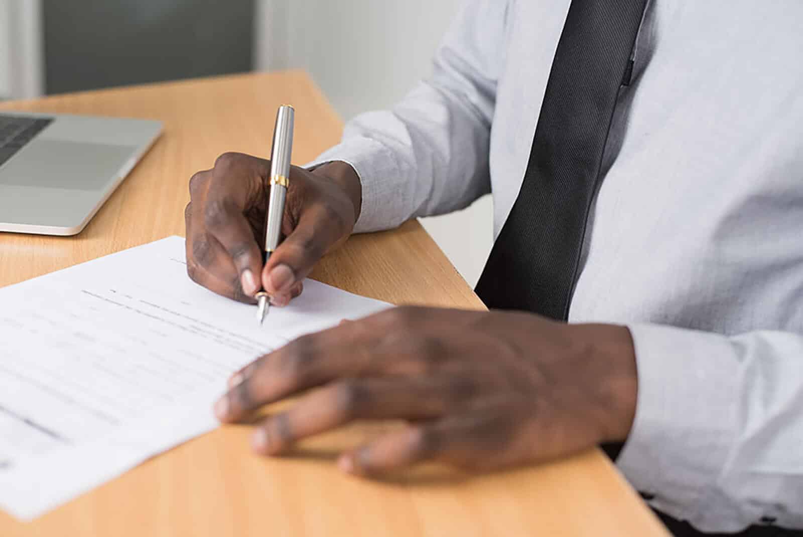 man holding pen writing on a piece of paper